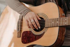 A close-up of a woman's hand strumming an acoustic guitar, showcasing musical passion.